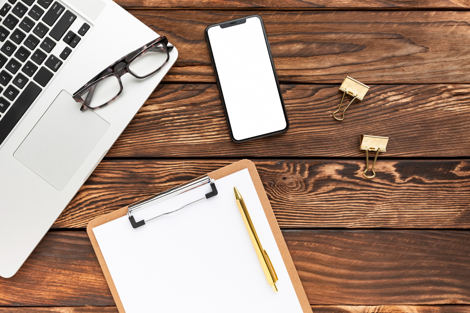Laptop, phone, and clipboard on desk for website tracking setup